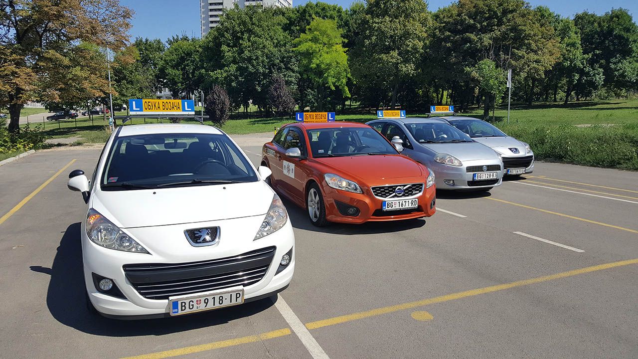 Beli Peugeot 207 u prvom planu, iza njega Volvo C30 i ostala vozila škole na poligonu