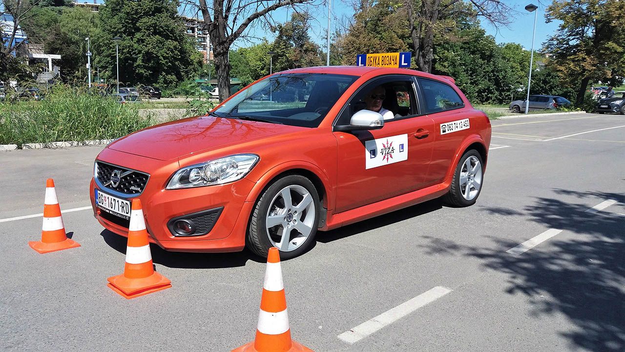 Crveni Volvo C30 Auto škole Viza sa oznakom škole i čunjevima na poligonu